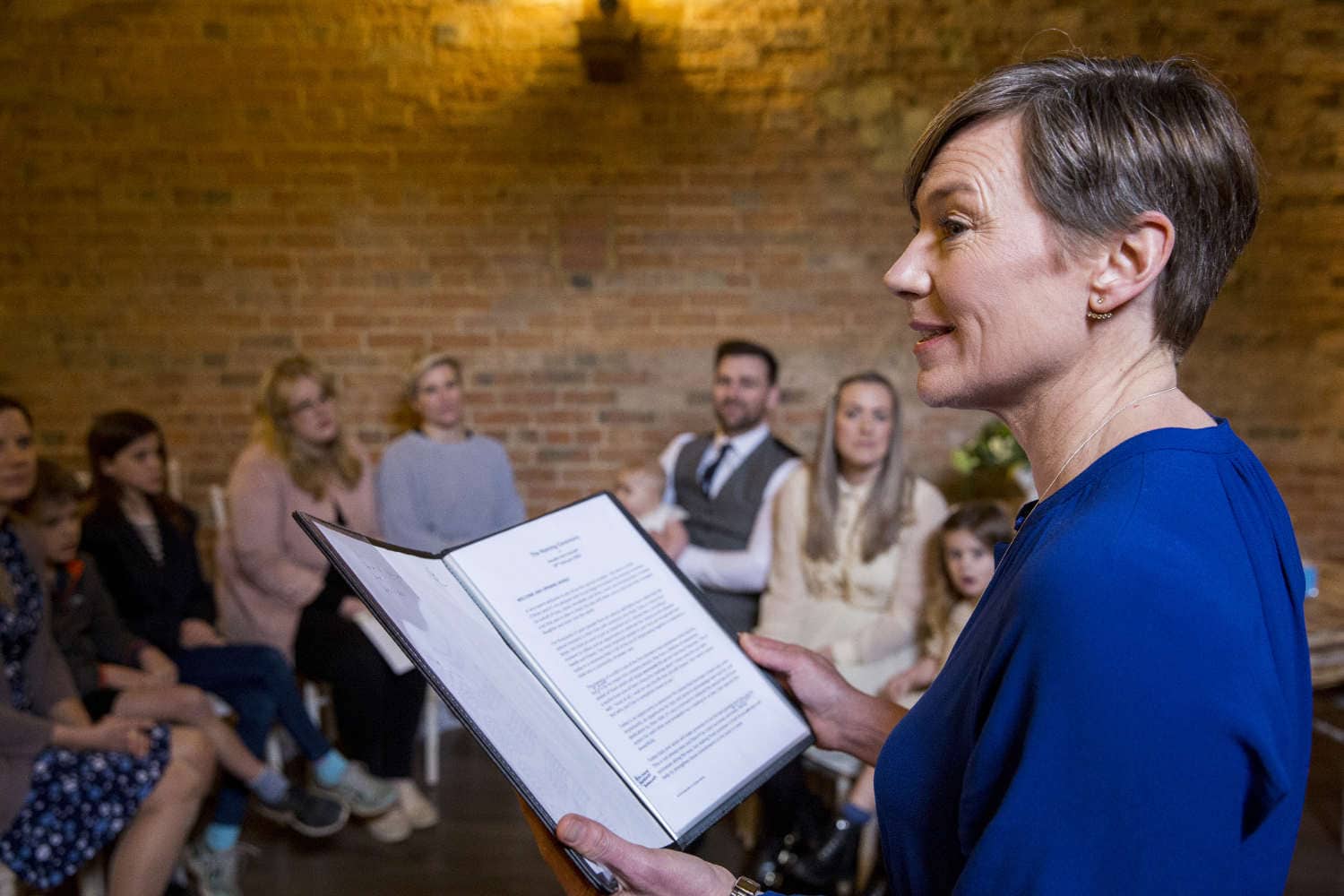 Celebrant performing naming ceremony for parents and their baby daughter in an historic barn.